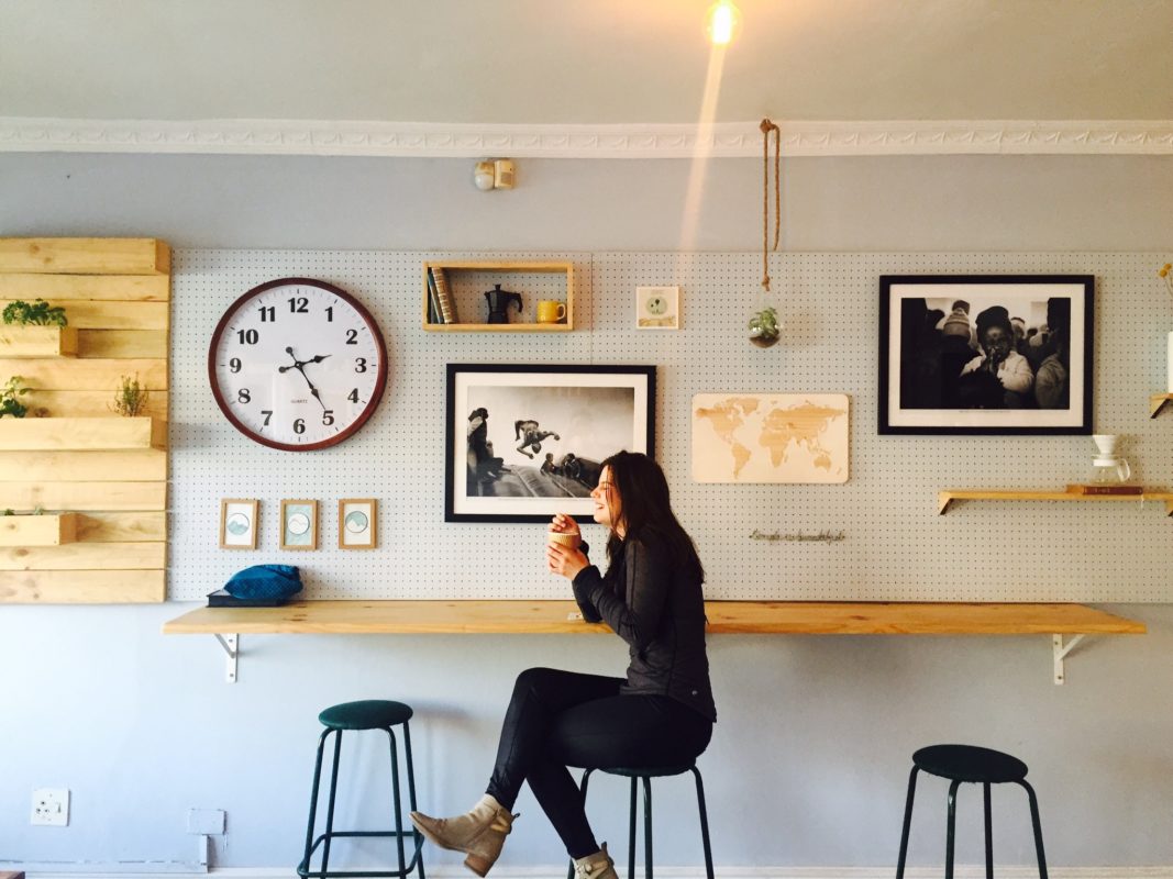 Roamlike Frau an Theke mit Kaffee. Uhr und Kunst an der Wand
